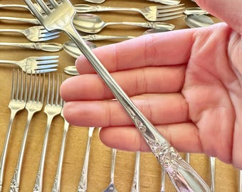 May include: A set of silver flatware with ornate handles. The set includes forks and spoons.