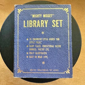 Puede incluir: Un juego de biblioteca "Mighty Midget" vintage con 15 pequeños libros encantadores para niños. La cubierta azul del libro tiene letras doradas y bordes decorativos. Contiene cuentos de hadas, poemas y acertijos.