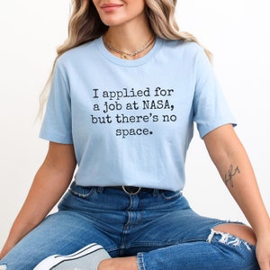 May include: A light blue t-shirt with the text "I applied for a job at NASA, but there's no space."