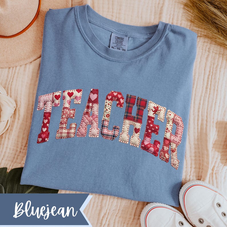 May include: A bluejean-coloured t-shirt with the word "TEACHER" appliqu&eacute;d across the front in a patchwork design. The patchwork includes hearts and plaid patterns. The shirt is a Comfort Colors brand, size XL-TG-EG.
