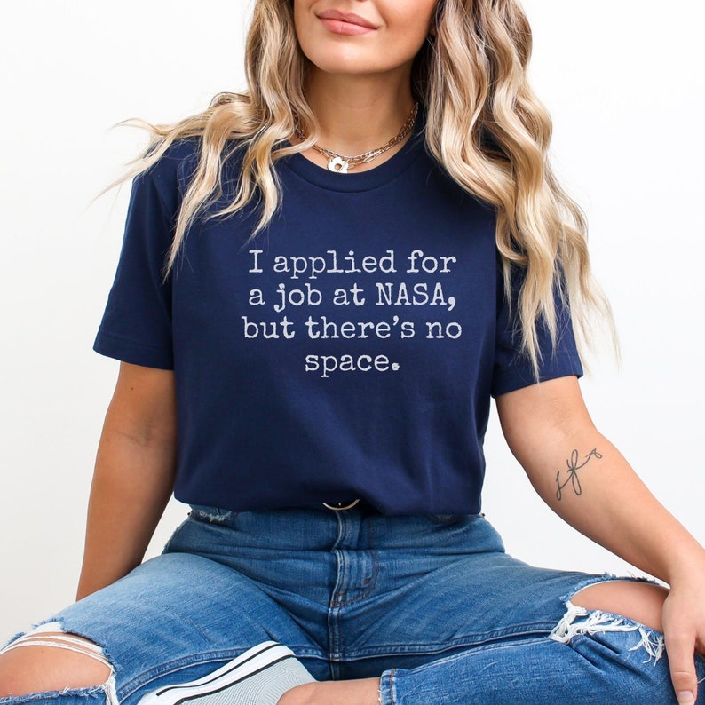 May include: A navy blue t-shirt with the text "I applied for a job at NASA, but there's no space." printed in white.