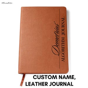 May include: A rectangular brown journal with a textured cover. The front features a vertical black line separating the name Demetrius in a cursive script from the text ALGORITHM JOURNAL in a bold, sans-serif font. A small bookmark ribbon extends from the bottom.