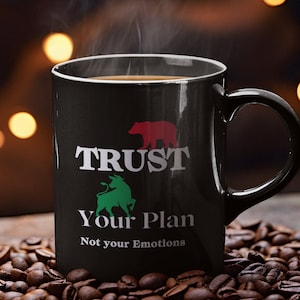 May include: Black coffee mug with a white graphic that says "Trust Your Plan, Not Your Emotions". The graphic also includes a red bear and a green bull.