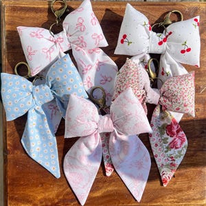 ¡Adorables llaveros con lazo cosidos a mano, perfectos para cualquier bolso o cartera!