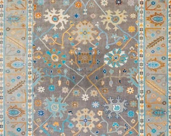 May include: A rectangular area rug with an intricate floral design. The rug features a gray background with a central medallion and a border. The design incorporates shades of blue, orange, and cream, creating a detailed and ornate pattern.