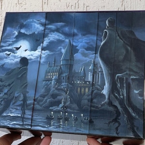 Könnte beinhalten: Eine dunkelblaue Box mit einer detaillierten Illustration von Hogwarts, einer dunklen Gestalt in einem Umhang und einem Halbmond. Die Box ist ein Sammlerstück für Fans der Harry Potter-Reihe.