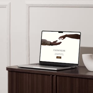 May include: A laptop computer open to a website with a white background and the text "Caleb & Willow" in black. The website features a silhouette of two hands reaching towards each other.