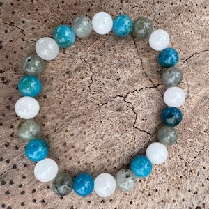 May include: A bracelet made of white, blue, and gray beads. The beads are round and have a smooth, polished finish.