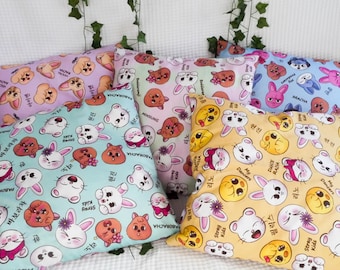 May include: A collection of colorful throw pillows with cartoon animal and text designs. Pillows feature bunnies, bears, and other characters in various colors, including blue, yellow, pink, and purple. The pillows have text in Korean.