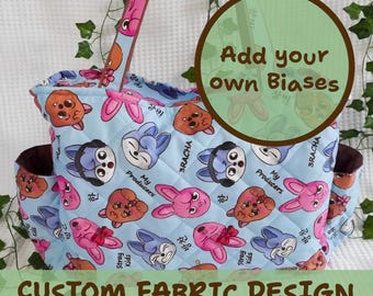 May include: A light blue tote bag with a quilted pattern featuring cartoon animal faces. The bag has brown accents, side pockets, and handles. Text on the bag reads "My Producers", "Stray Kids", and "Custom Fabric Design". A circular graphic says "Add your own Biases".