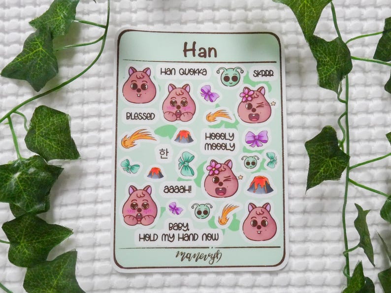May include: A sticker sheet with a light green background featuring various cartoon images and text. The images include pink bear-like characters, butterflies, volcanoes, and shooting stars. Text includes "Han", "Blessed", "Baby, Hold My Hand Now", and other phrases.