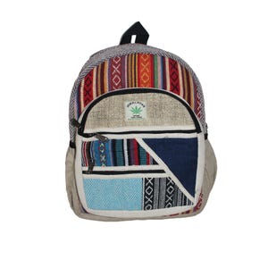 May include: A patterned backpack with a mix of colours and textures. The main section has vertical stripes in red, orange, and purple. The front pocket features a patchwork design with blue, white, and black details. The text "Himalayan Hemp THC Free" is visible.