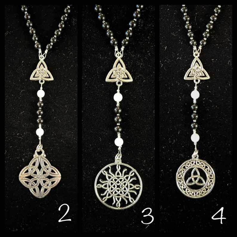 May include: Three black beaded necklaces with silver Celtic knot pendants. The first necklace has a simple triangular knot pendant. The second necklace has a square knot pendant. The third necklace has a circular knot pendant with a sunburst design.