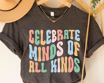 May include: Dark grey heather t-shirt with the text "Celebrate Minds of All Kinds" in colorful, retro-style lettering.