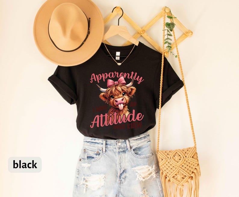May include: Black t-shirt with a cartoon Highland cow with a pink bow and the text "Apparently I Have An Attitude Problem".