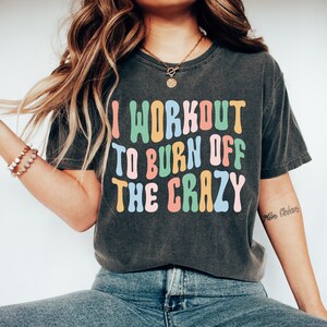 May include: A black t-shirt with the text "I workout to burn off the crazy" in colorful, outlined letters. The text is in a retro font style.