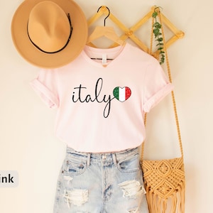 May include: Pink t-shirt with the word "italy" in cursive script and a heart-shaped Italian flag graphic.