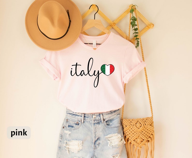 May include: Pink t-shirt with the word "italy" in cursive script and a heart-shaped Italian flag graphic.