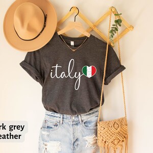 May include: Dark grey heather t-shirt with the word "italy" in white script and a heart with the Italian flag inside.