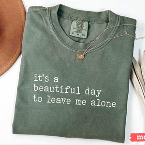 May include: A green t-shirt with the text "it's a beautiful day to leave me alone" printed in white.