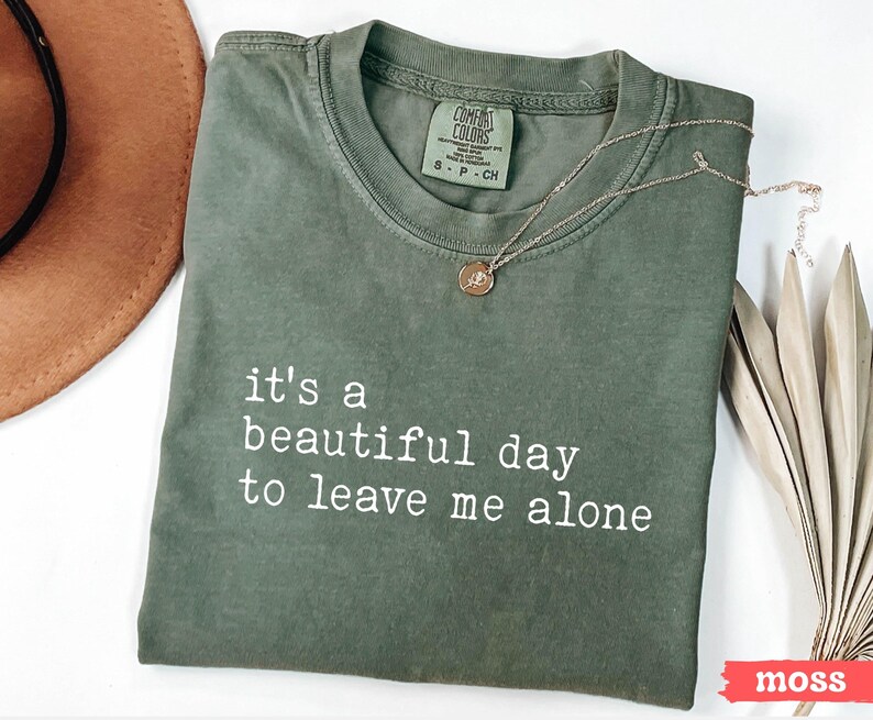 May include: A green t-shirt with the text "it's a beautiful day to leave me alone" printed in white.