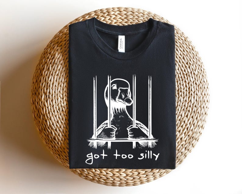 May include: Black t-shirt with a white graphic of a goose in a cage. The text "got too silly" is printed below the image.