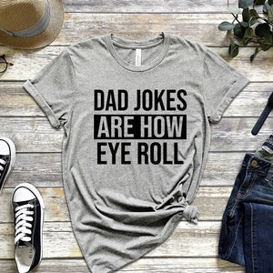 May include: Gray t-shirt with black text that reads "Dad Jokes Are How Eye Roll".