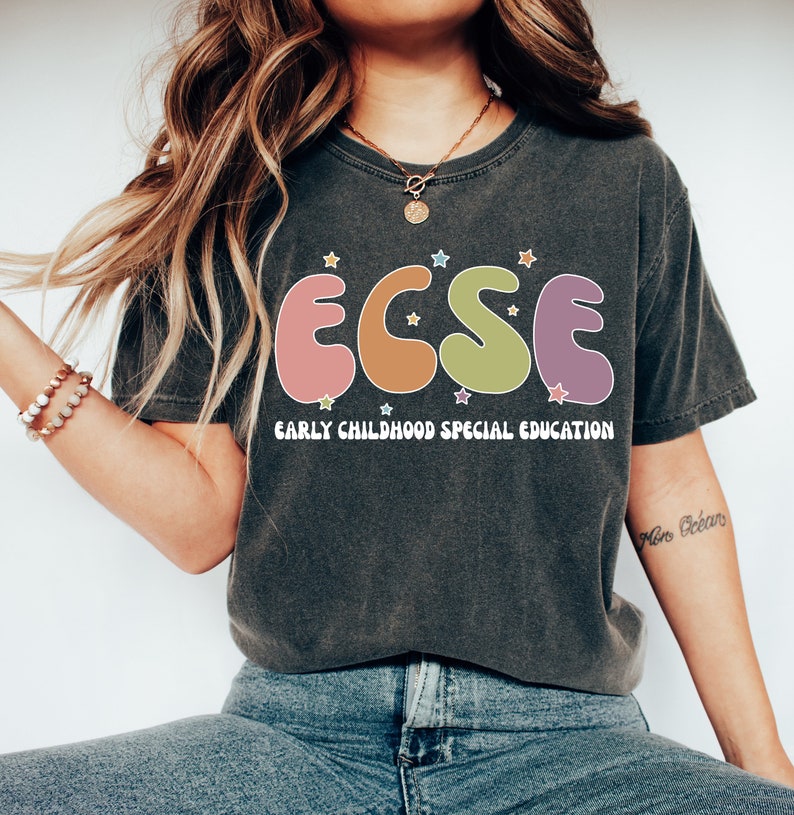 K&ouml;nnte beinhalten: Ein dunkelgraues T-Shirt mit einer bunten Grafik der Buchstaben "ECSE" im Retro-Stil. Die Buchstaben sind von kleinen wei&szlig;en Sternen umgeben. Unter der Grafik ist der Text "EARLY CHILDHOOD SPECIAL EDUCATION" in Wei&szlig; gedruckt.