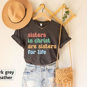 May include: Dark grey heather t-shirt with the text "sisters in christ are sisters for life" in colorful letters.