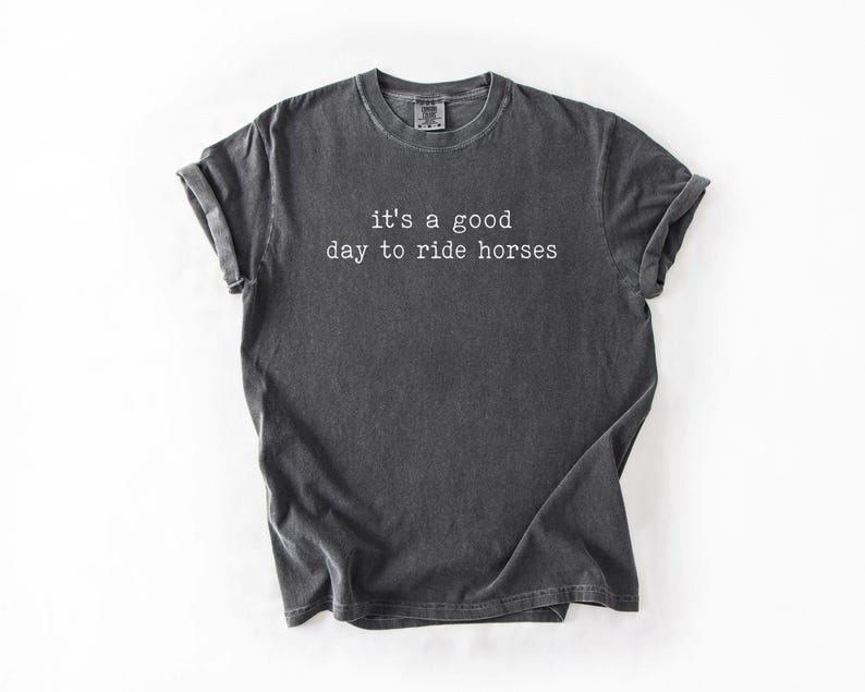 May include: A dark gray t-shirt with the text "it's a good day to ride horses" printed in white.