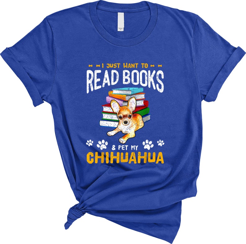 May include: A royal blue t-shirt with the text "I just want to read books & pet my chihuahua" in yellow. A chihuahua is sitting on a stack of books.