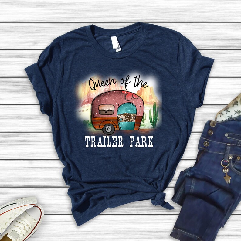 May include: A navy blue t-shirt with the text "Queen of the Trailer Park" and a cartoon image of a camper van in a desert landscape.