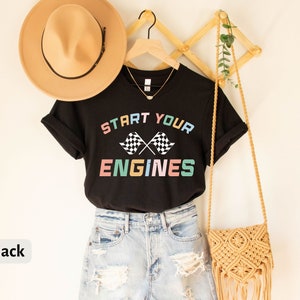 May include: Black t-shirt with the text "Start Your Engines" in rainbow colors and a checkered flag graphic.