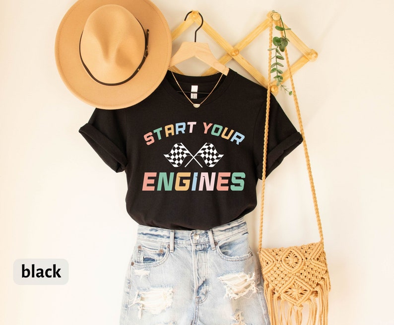 May include: Black t-shirt with the text "Start Your Engines" in rainbow colors and a checkered flag graphic.