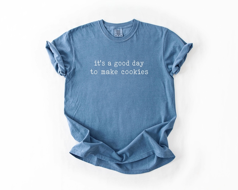 May include: A blue t-shirt with the text "it's a good day to make cookies" printed in white.