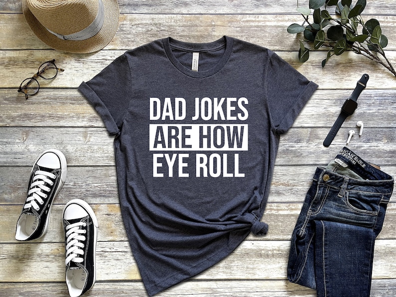 May include: A dark gray t-shirt with white text that reads "Dad Jokes Are How Eye Roll".