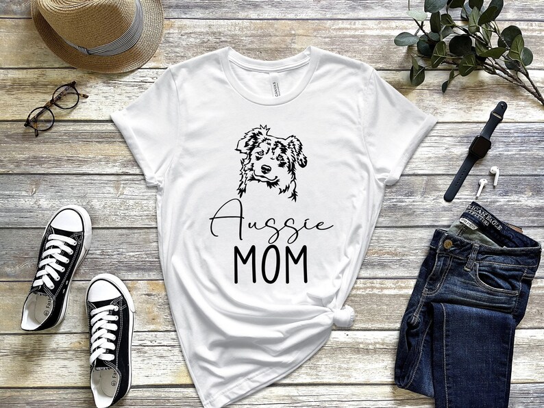 K&ouml;nnte beinhalten: Wei&szlig;es T-Shirt mit einer Schwarzwei&szlig;illustration eines Australian Shepherds und dem Text "Aussie MOM".