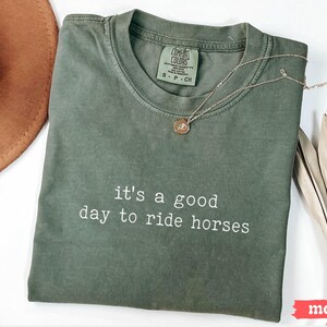 May include: A green t-shirt with the text "it's a good day to ride horses" printed in white. The shirt is made by Comfort Colors and has a tag that says "S-P-CH".