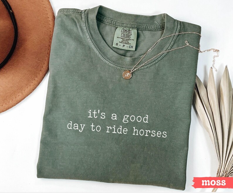 May include: A green t-shirt with the text "it's a good day to ride horses" printed in white. The shirt is made by Comfort Colors and has a tag that says "S-P-CH".