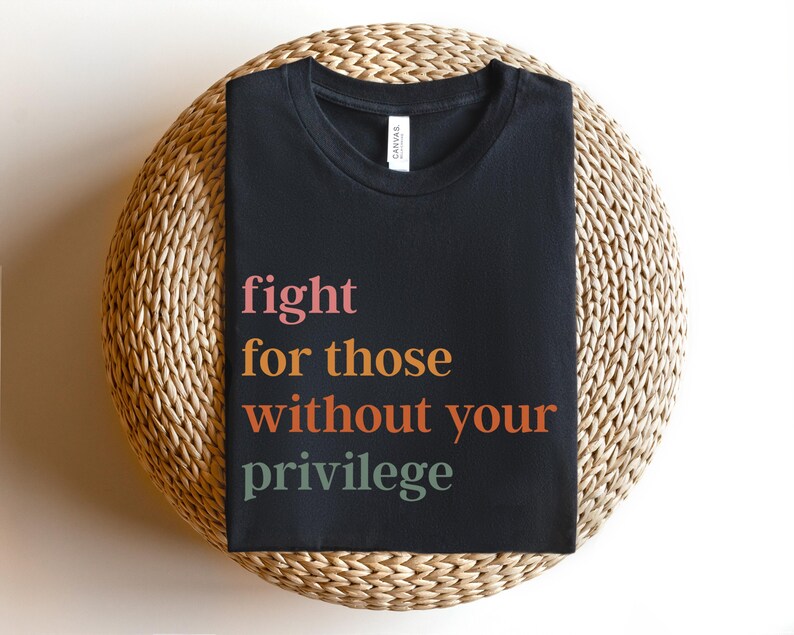 Op de afbeelding: Zwart T-shirt met de tekst "fight for those without your privilege" in kleurrijke letters.