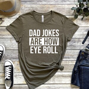 May include: A green t-shirt with white text that reads "Dad Jokes Are How Eye Roll".