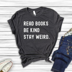 May include: A dark gray t-shirt with the text "Read Books Be Kind Stay Weird." printed in white.