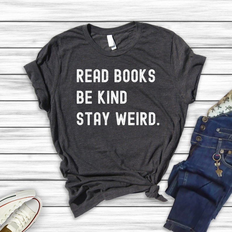 May include: A dark gray t-shirt with the text "Read Books Be Kind Stay Weird." printed in white.