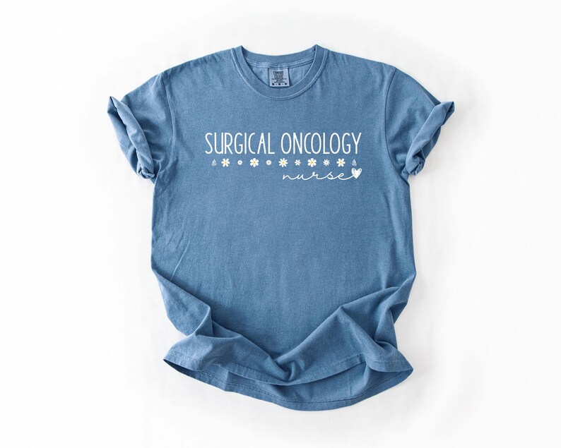May include: A blue t-shirt with the text "SURGICAL ONCOLOGY nurse" in white lettering with small flower accents.
