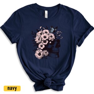 May include: A navy blue t-shirt with a graphic of a skull with pink flowers and a blue butterfly.