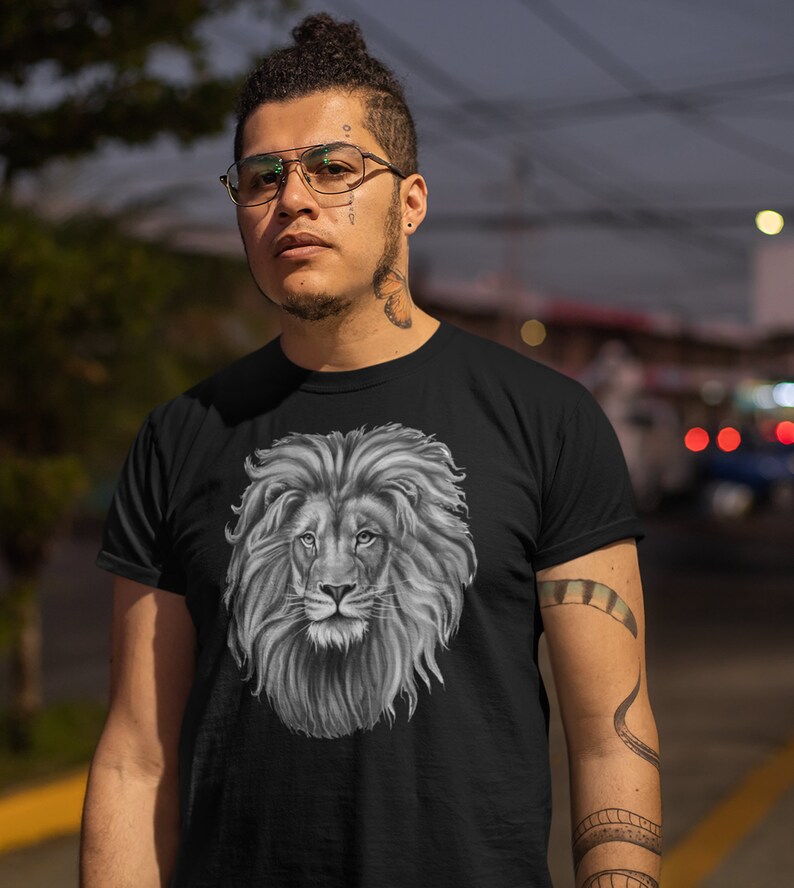 Może przedstawiać: Czarny t-shirt z grafiką głowy lwa w czerni i bieli. Lew ma pełną grzywę i patrzy bezpośrednio na widza.