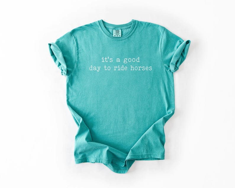 May include: Teal blue t-shirt with the text "it's a good day to ride horses" in white.
