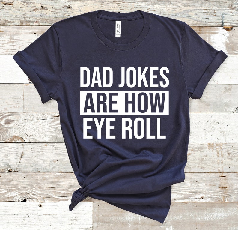 May include: A navy blue t-shirt with white text that reads "Dad Jokes Are How Eye Roll".