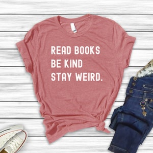 May include: A red heather t-shirt with the text "Read Books Be Kind Stay Weird." printed in white.