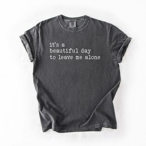 May include: A dark gray t-shirt with the text "it's a beautiful day to leave me alone" printed in white.